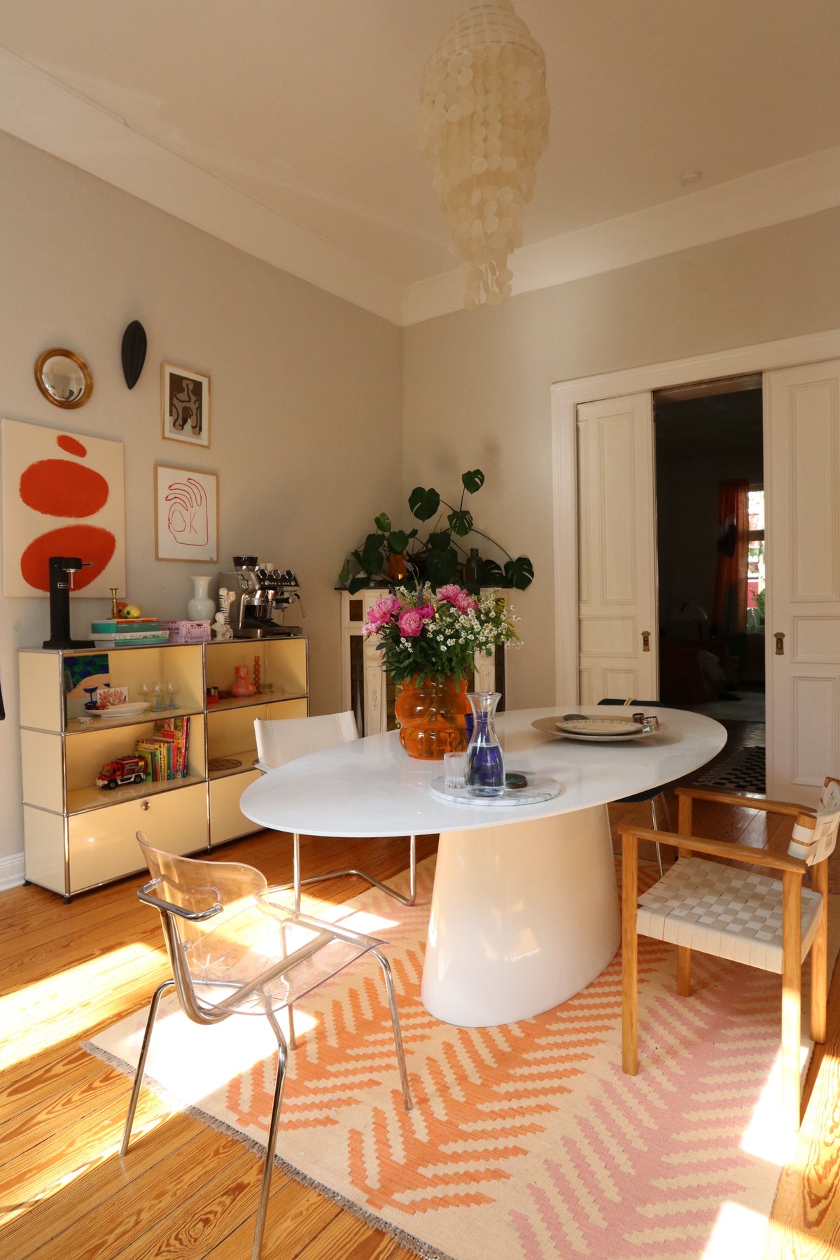 Dining area with an oval table, chairs, and a patterned rug on a wooden floor.