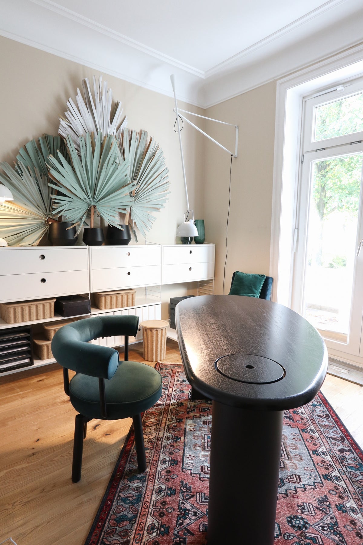 Home office with a dark desk, green armchair, and patterned rug on a wooden floor.
