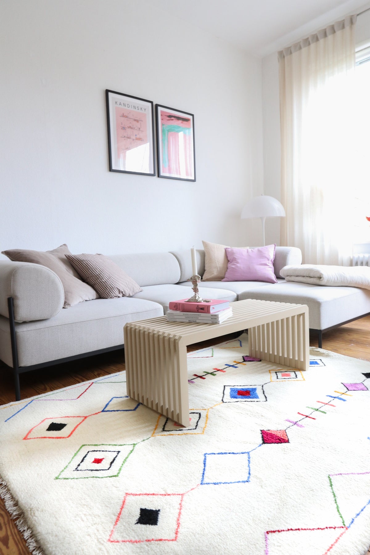 Bright living room with a sofa, coffee table, and white rug with colorful geometric patterns.