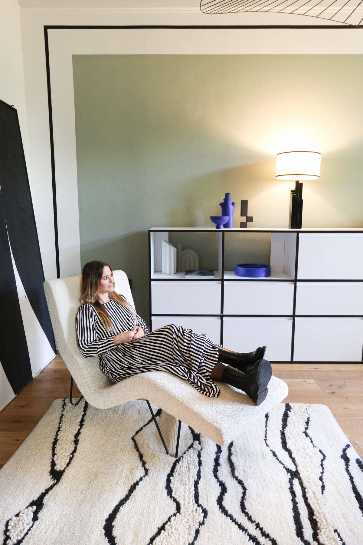Woman lying on a chaise lounge on a patterned rug in the living room.