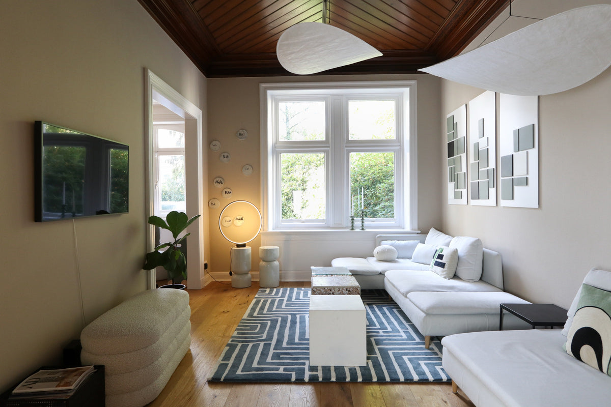 Bright living room with a white sectional sofa, geometric patterned rug, and coffee tables.